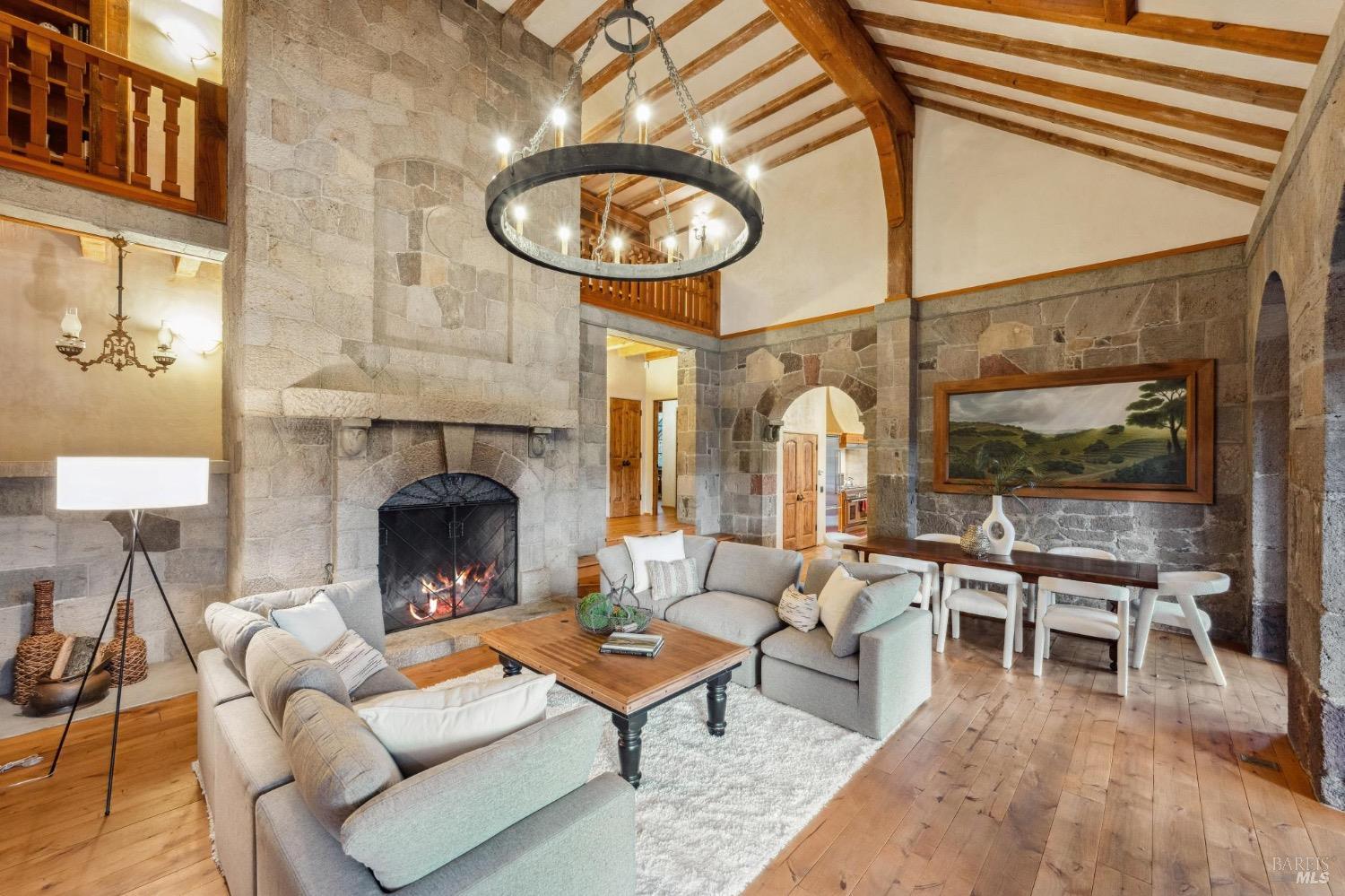 The great room of Casa de Chamizal: hand-laid stone walls, timber beams, an iron chandelier and a roaring stone fireplace.